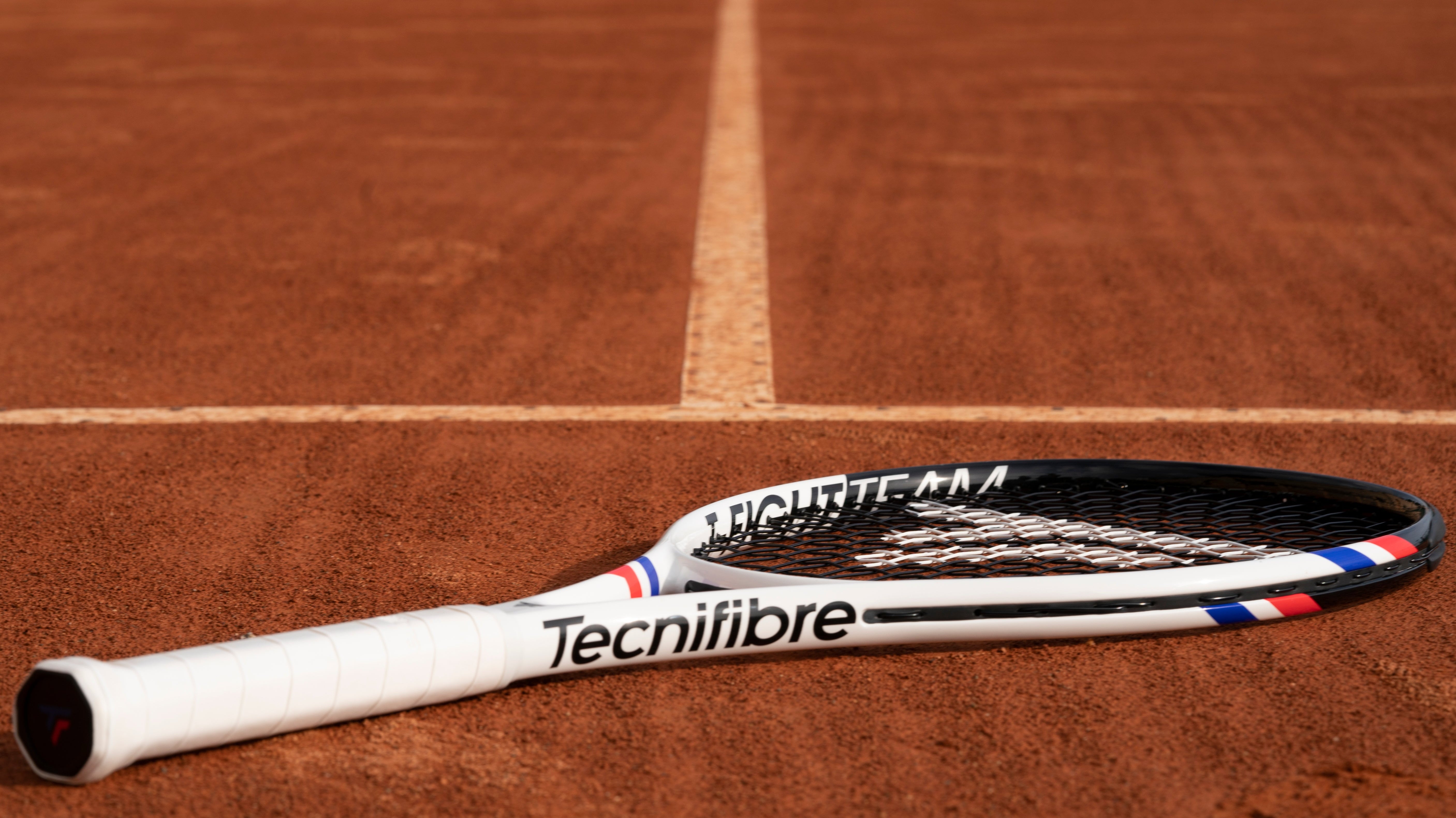 Tecnifibre T-Fight racket lying on a clay court
