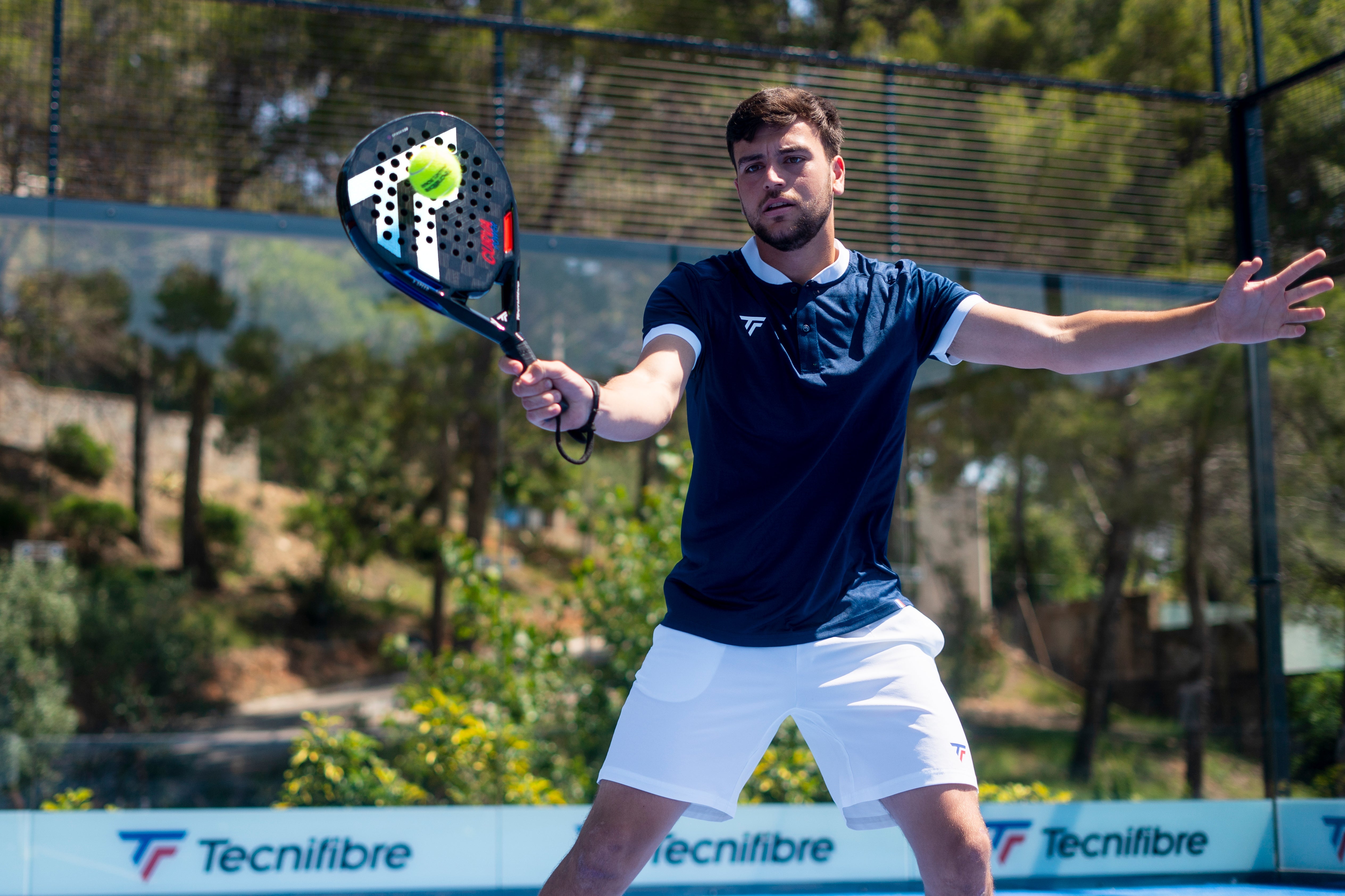 Padel player mid-swing on an outdoor court