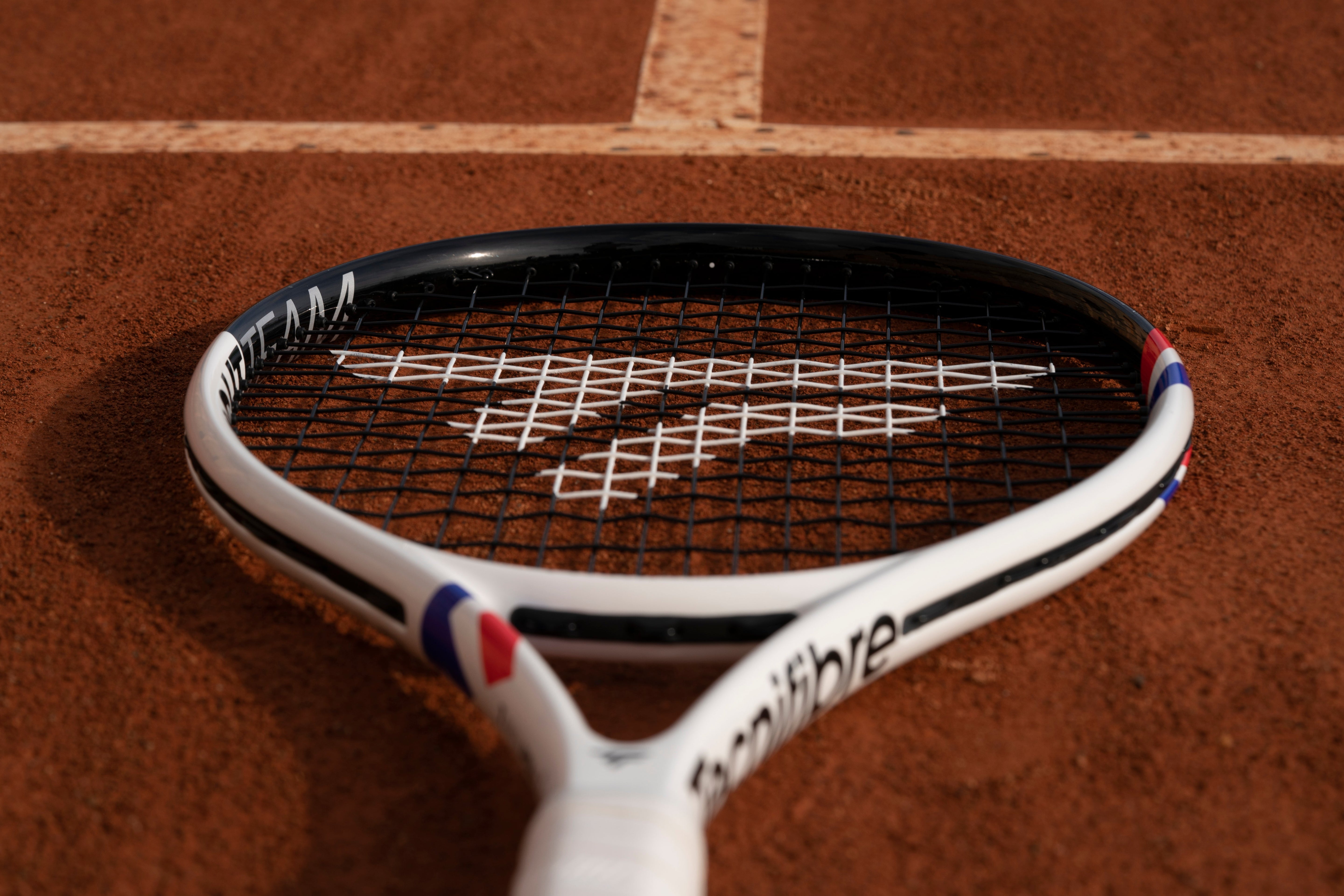 White Tecnifibre T-Fight racket head resting on a clay court