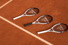 Three white Tecnifibre T-Fight tennis rackets laid out on a clay court
